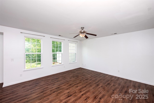 empty room featuring dark wood-style flooring, a ceiling fan, and baseboards