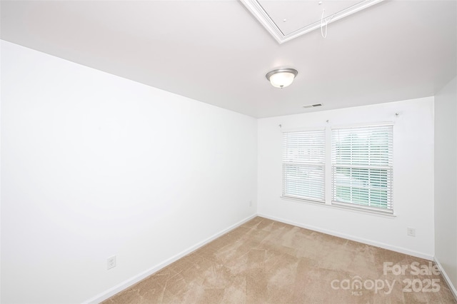 unfurnished room featuring attic access, baseboards, and light colored carpet