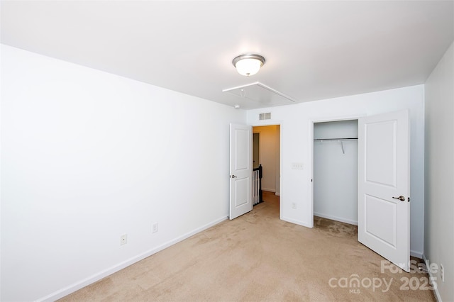 unfurnished bedroom featuring attic access, light carpet, baseboards, and a closet