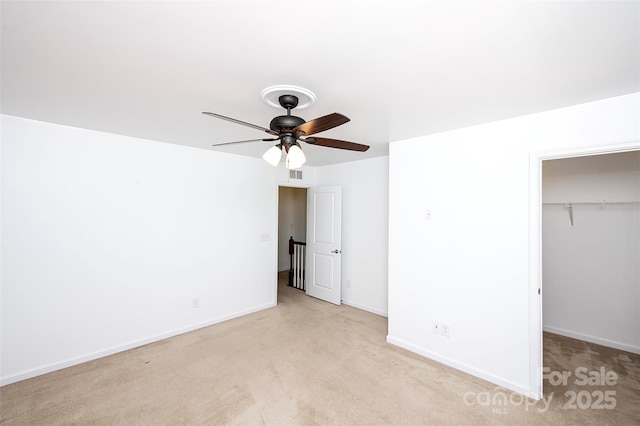 unfurnished bedroom with light carpet, a walk in closet, a closet, and baseboards