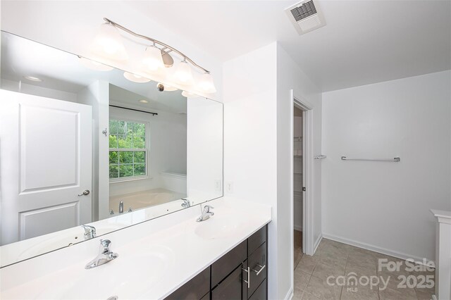 bathroom featuring double vanity, a bath, tile patterned flooring, and baseboards