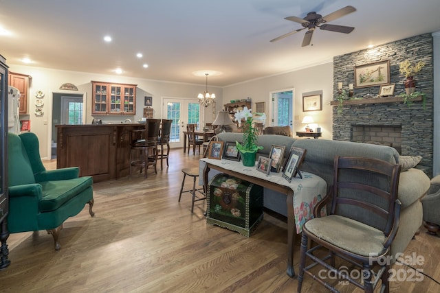 4398 Mud Puddle Ln, Lenoir, NC 28645 - living room featuring a chandelier, wood finished floors, ceiling fan, crown molding, and a stone fireplace