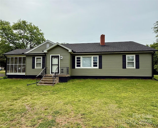 view of front of home featuring a chimney, a front lawn, a sunroom, and roof with shingles