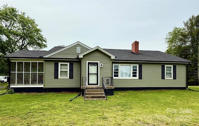 view of front facade with a chimney, a front yard, and a sunroom