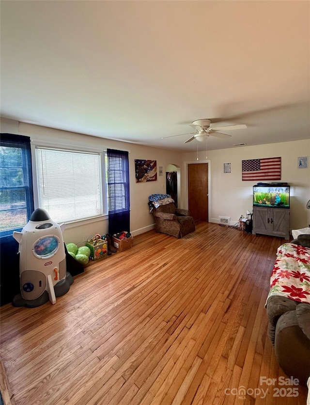 living room featuring wood-type flooring, ceiling fan, and baseboards