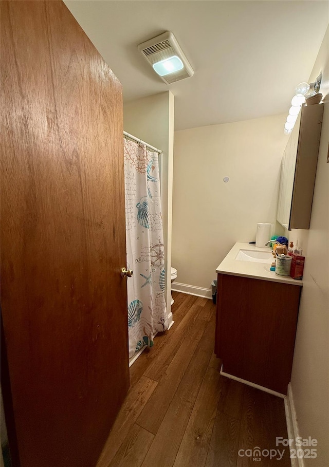 bathroom with wood finished floors, toilet, vanity, baseboards, and a shower with shower curtain