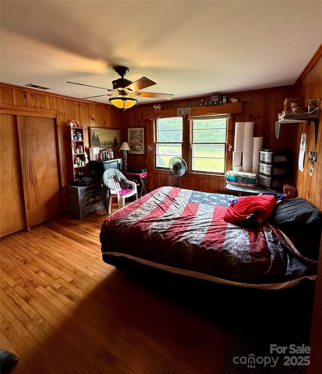 bedroom featuring wood walls, light wood finished floors, and ceiling fan