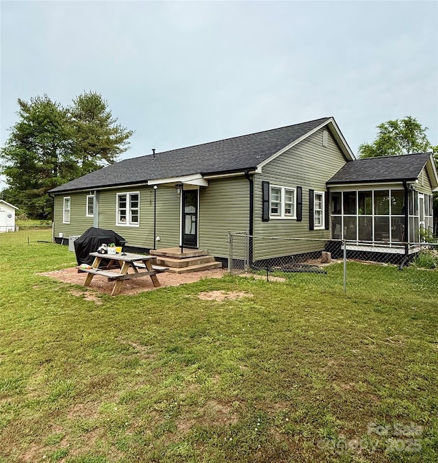 back of house with a sunroom and a lawn