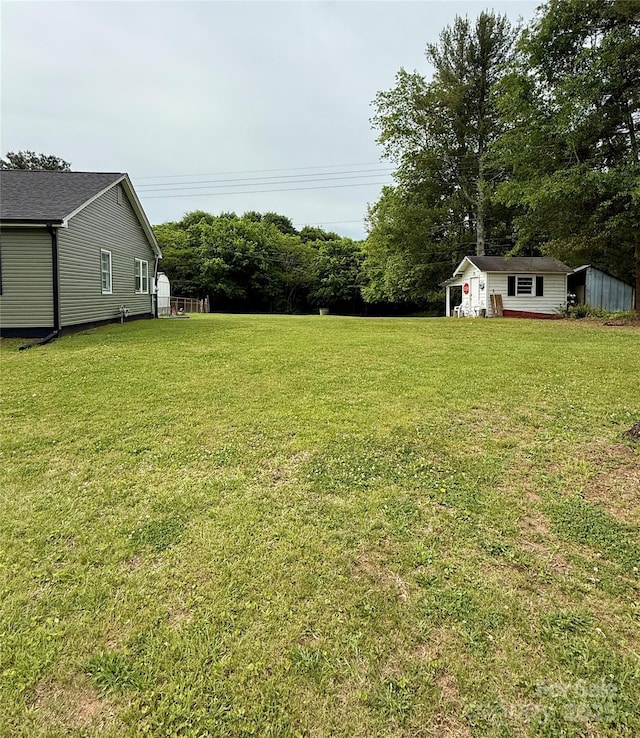 view of green lawn featuring an outbuilding