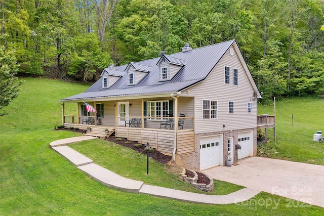 view of front of home featuring a garage, covered porch, a front yard, and metal roof