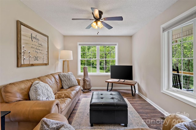living area featuring baseboards, a ceiling fan, a textured ceiling, and dark wood-style floors