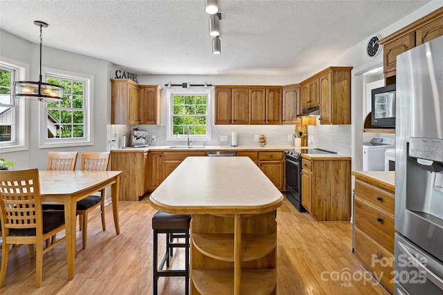 423 Cad Campbell Rd, Bakersville, NC 28705 - kitchen with electric range, stainless steel fridge with ice dispenser, washing machine and dryer, under cabinet range hood, and light wood-type flooring