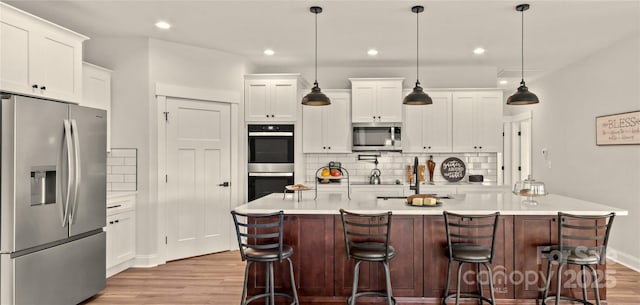 LOT101 Coppergate Dr, Salisbury, NC 28147 - kitchen featuring appliances with stainless steel finishes, light wood finished floors, decorative backsplash, light countertops, and recessed lighting