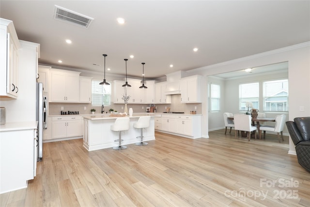 1119 Bellshill Dr, Indian Trail, NC 28079 - kitchen featuring crown molding, a kitchen island, light countertops, stovetop, and light wood-type flooring
