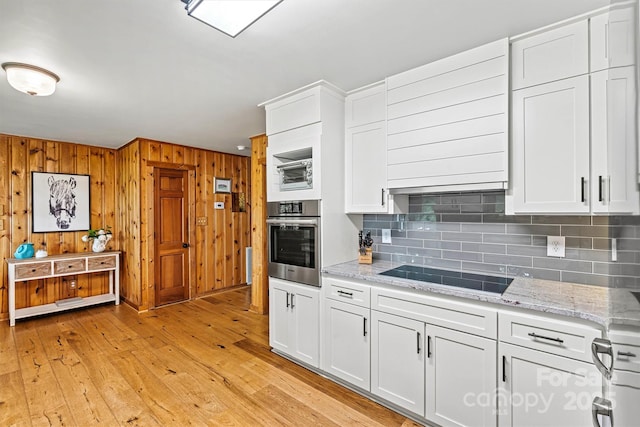 8218 Bright Water Ln, Denver, NC 28037 - kitchen featuring oven, black electric stovetop, decorative backsplash, light wood-style floors, and wood walls