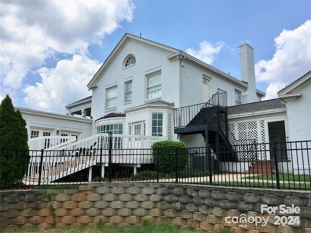 rear view of house featuring stairway, a chimney, and an attached garage