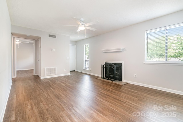 unfurnished living room featuring ceiling fan, wood finished floors, and a fireplace with raised hearth