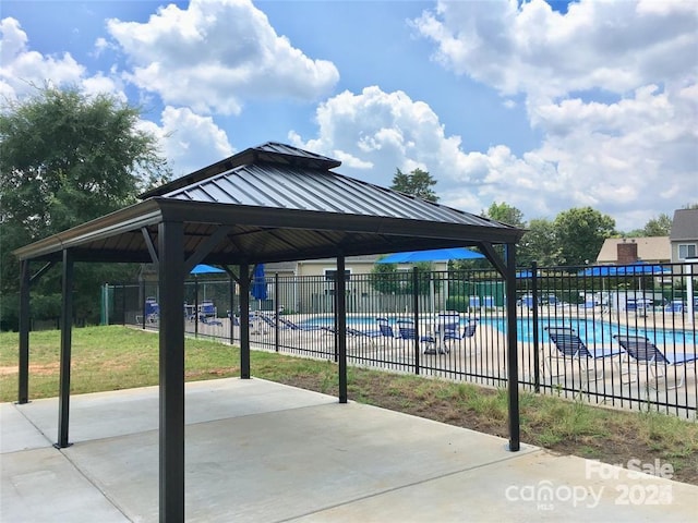view of patio featuring fence, a community pool, and a gazebo