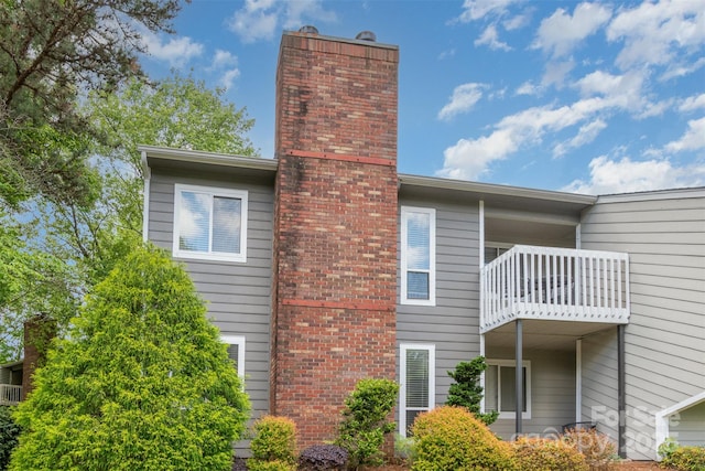 view of side of property featuring a chimney and a balcony