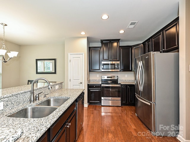 1769 Evergreen Dr, Charlotte, NC 28208 - kitchen featuring appliances with stainless steel finishes, dark wood-style floors, a chandelier, hanging light fixtures, and light stone counters