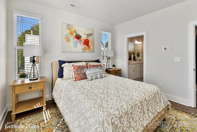 bedroom with baseboards, dark wood finished floors, and ensuite bathroom