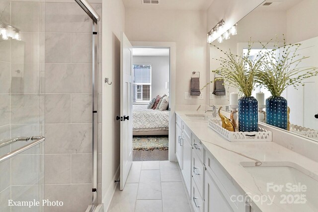 ensuite bathroom with a shower stall, double vanity, and tile patterned flooring