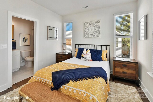 bedroom with wood finished floors, ensuite bath, and baseboards