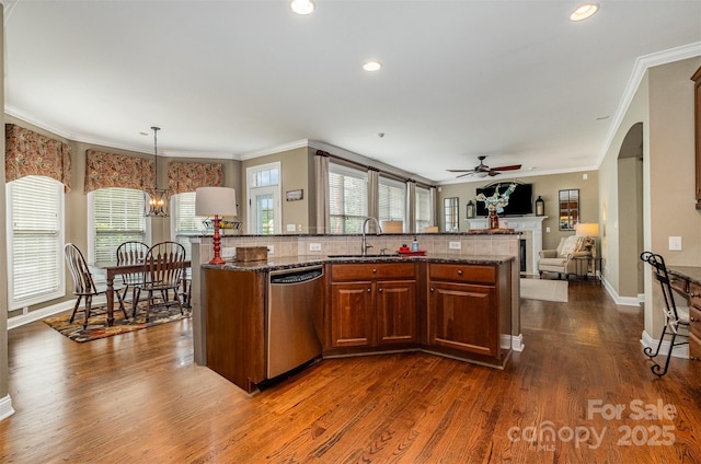 kitchen featuring stainless steel dishwasher, open floor plan, a sink, ornamental molding, and ceiling fan