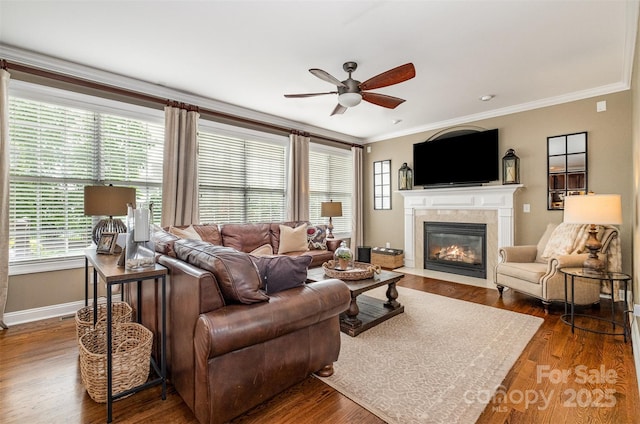 living room featuring ceiling fan, a fireplace with flush hearth, ornamental molding, baseboards, and healthy amount of natural light