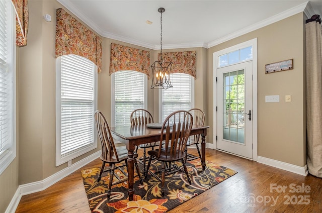 dining area featuring wood finished floors, a chandelier, baseboards, and ornamental molding