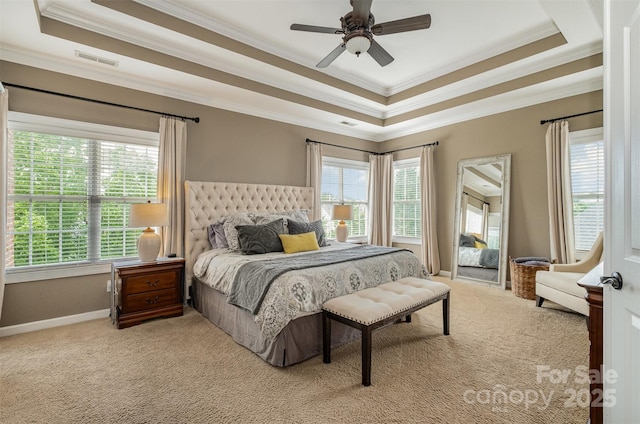carpeted bedroom featuring a raised ceiling, ornamental molding, multiple windows, baseboards, and ceiling fan