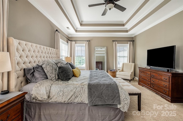 bedroom with a raised ceiling, light colored carpet, crown molding, and a ceiling fan