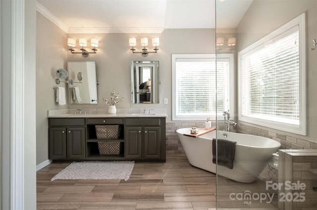 full bathroom with crown molding, a freestanding tub, tile walls, double vanity, and wainscoting