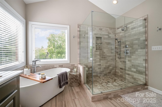 bathroom with healthy amount of natural light, a freestanding tub, a shower stall, recessed lighting, and lofted ceiling