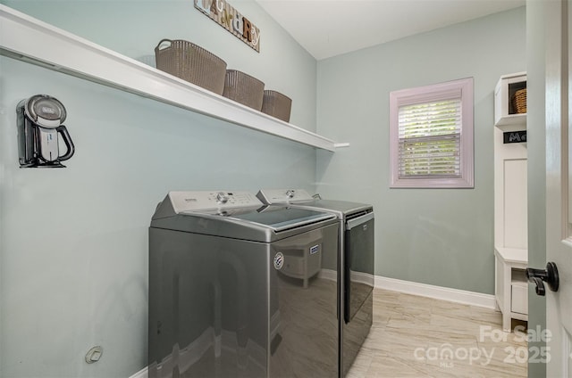 laundry room with washing machine and dryer, light marble finish flooring, and baseboards