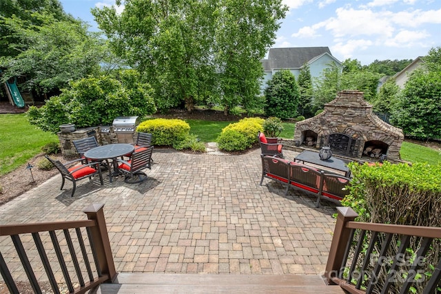 view of patio featuring an outdoor stone fireplace, outdoor dining area, and grilling area