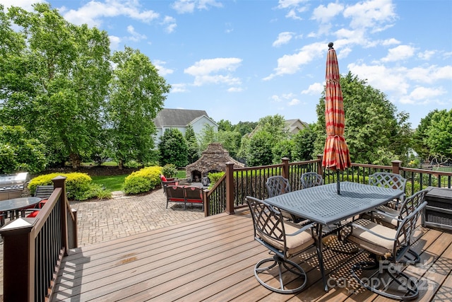 wooden terrace with a fireplace, outdoor dining area, and a patio area