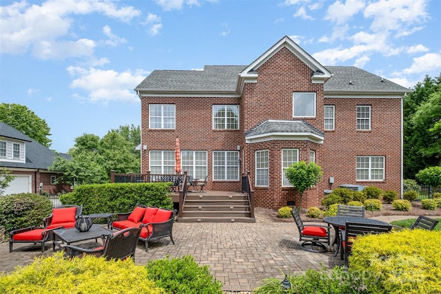 rear view of house featuring outdoor lounge area, brick siding, a wooden deck, and a patio
