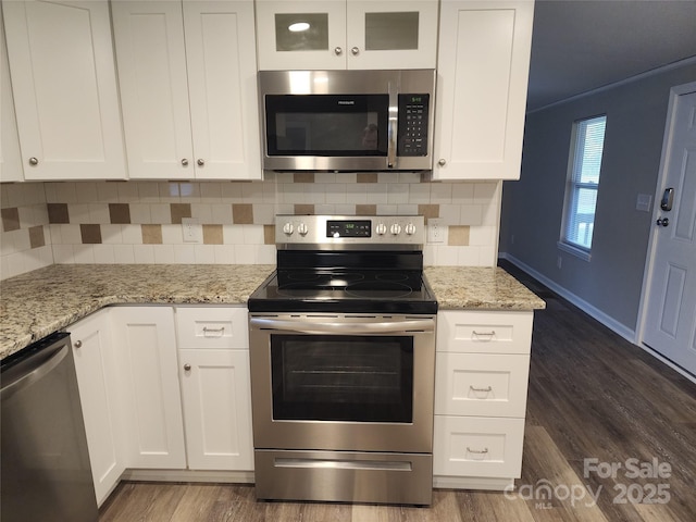 kitchen featuring stainless steel appliances, dark wood-style floors, white cabinetry, and decorative backsplash