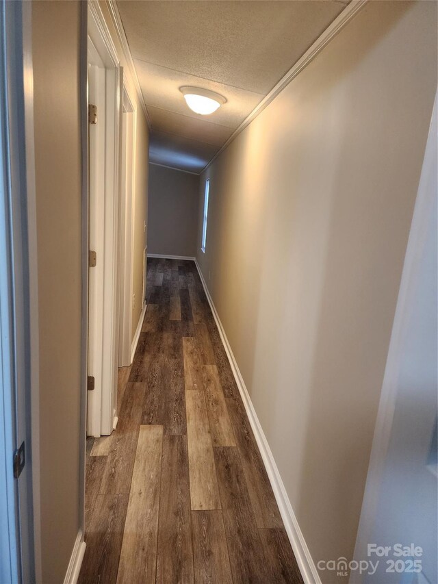 corridor featuring ornamental molding, dark wood finished floors, and a textured ceiling