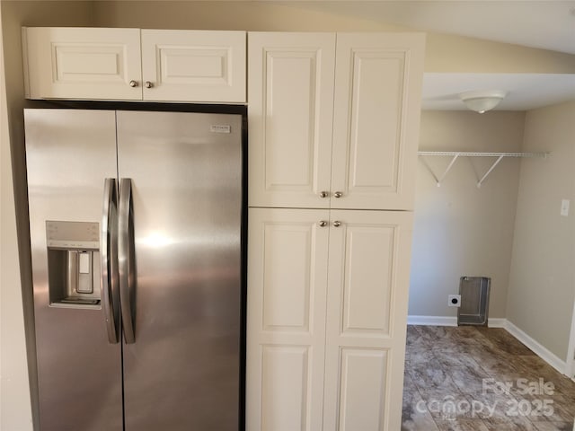 kitchen featuring stainless steel fridge, baseboards, and white cabinets