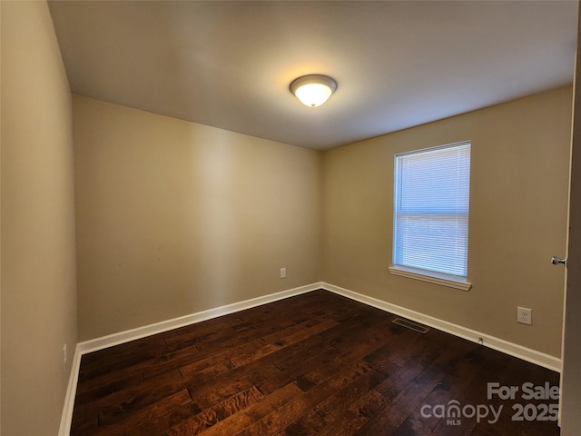 empty room featuring dark wood-style flooring and baseboards