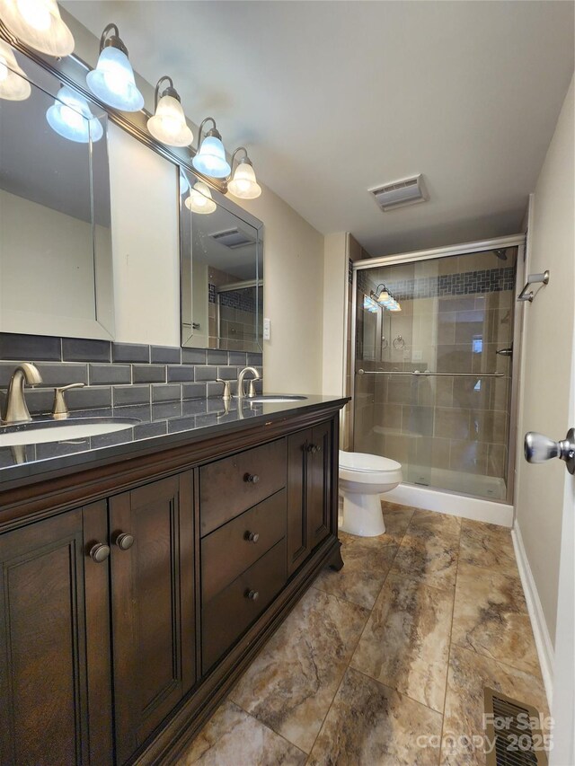 full bathroom featuring a shower stall, double vanity, toilet, tasteful backsplash, and baseboards