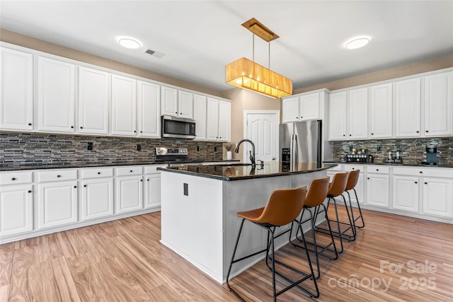 kitchen with stainless steel appliances, tasteful backsplash, light wood finished floors, and a breakfast bar area