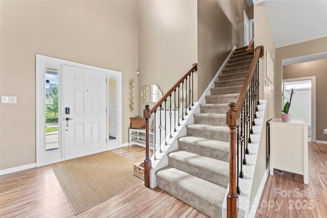 foyer featuring plenty of natural light, a high ceiling, stairway, and baseboards