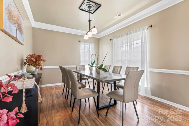 dining space featuring wood finished floors, ornamental molding, and baseboards