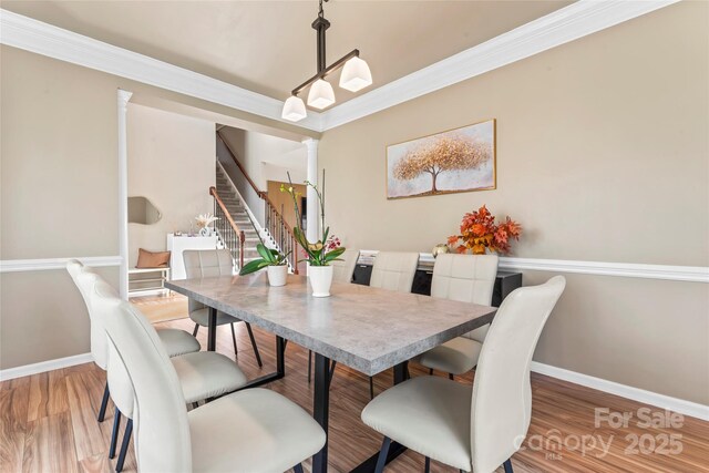 dining room with stairs, baseboards, wood finished floors, decorative columns, and ornamental molding