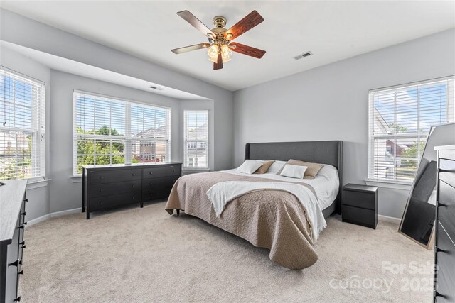 carpeted bedroom with multiple windows, baseboards, and a ceiling fan