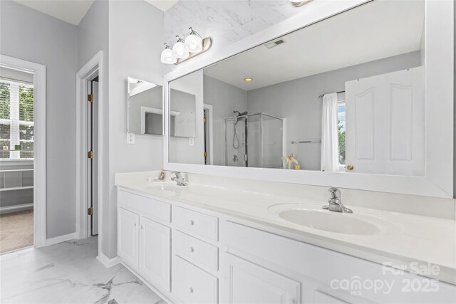 full bath featuring a stall shower, marble look tiles, double vanity, and baseboards