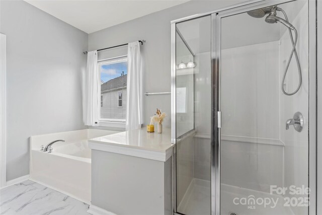 bathroom featuring a shower stall, a bath, and marble look tile flooring